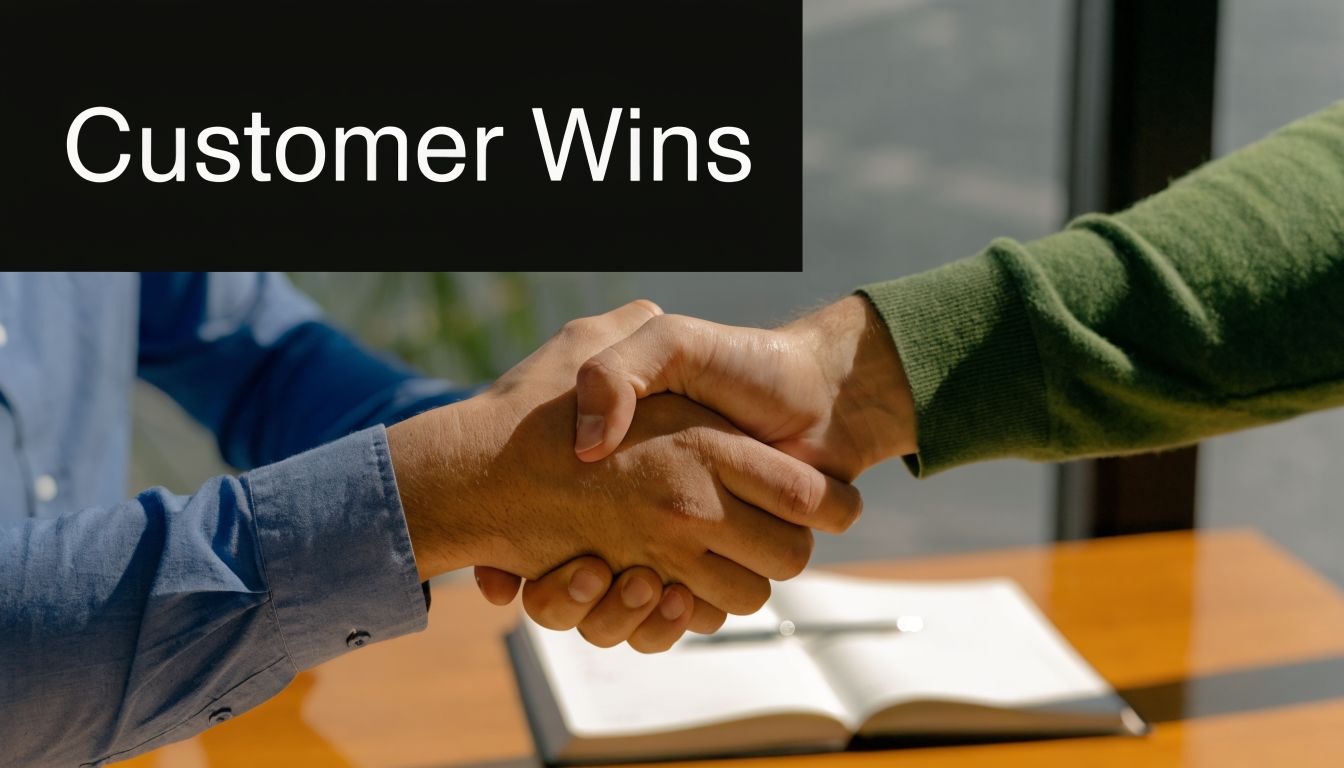 Two professional business partners shaking hands over a wooden desk with a notebook in a modern office.