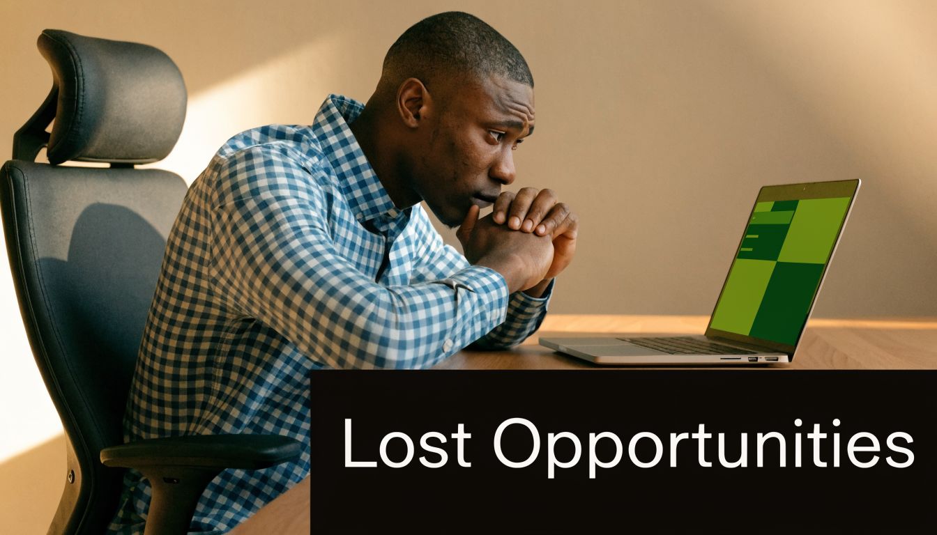 A focused man sitting at a desk looking at a green screen on his laptop computer.