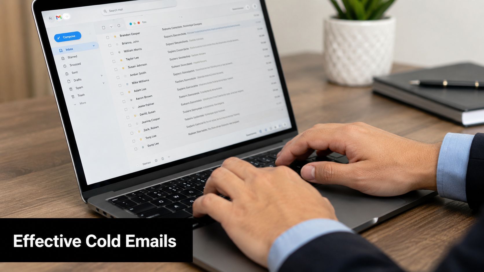 A professional in a suit typing on a laptop with an open email inbox on screen.